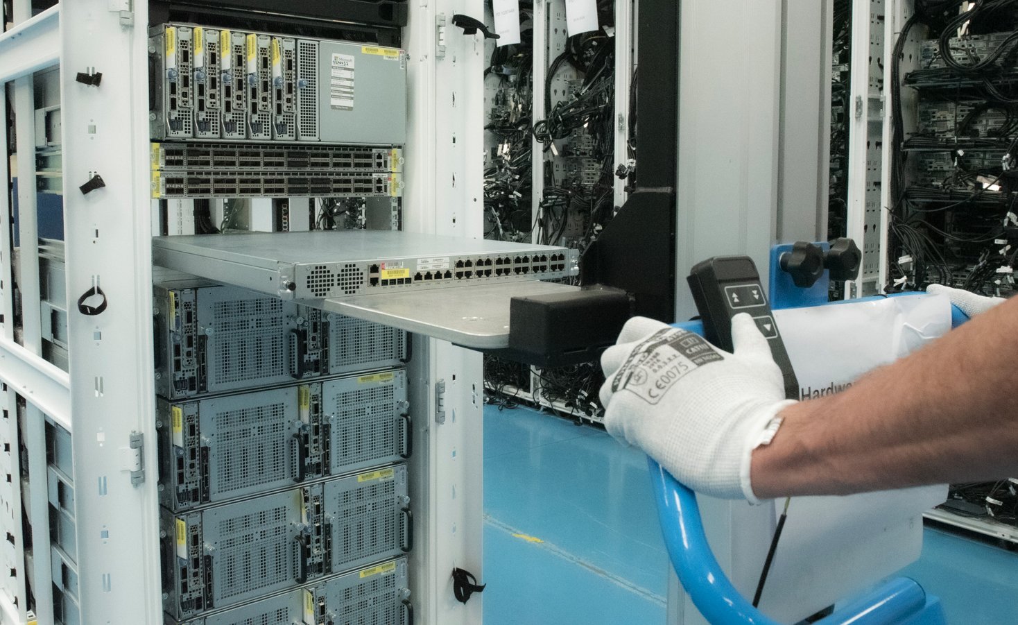 A technician moving a network switch into a rack with a lifting trolley